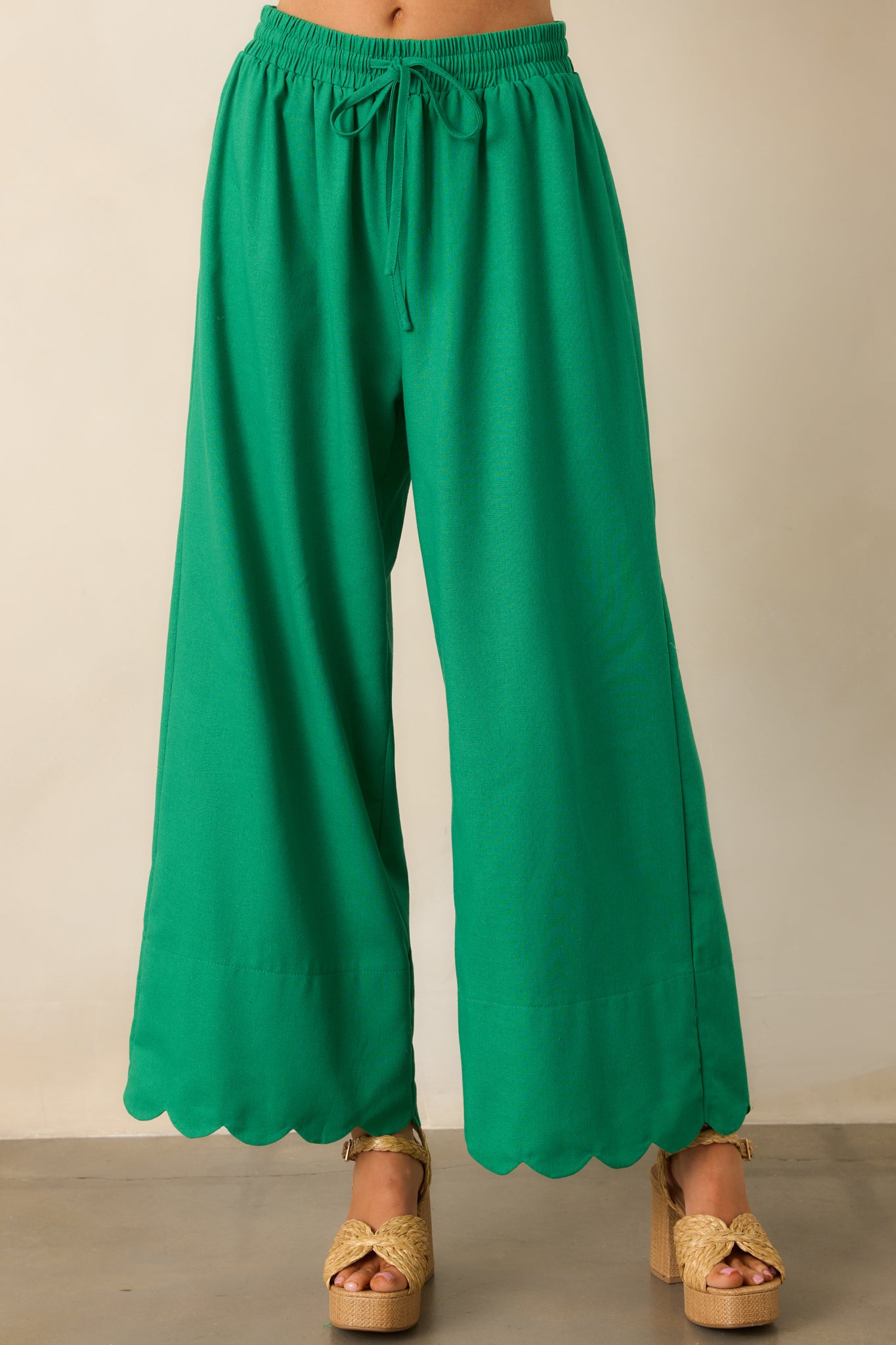 A detailed view of the scalloped bottom hem, bringing a unique and charming accent to these green pants.