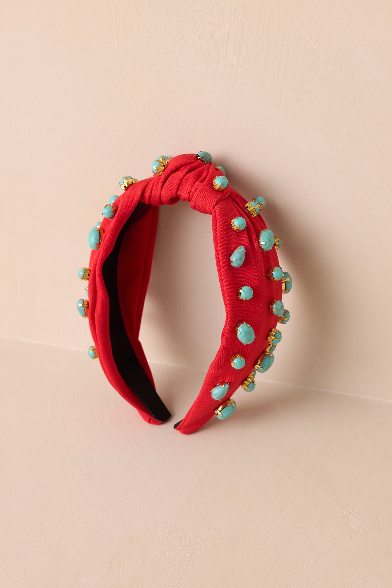 Red cloth headband with gold bordered turquoise beading, and a knotted top.
