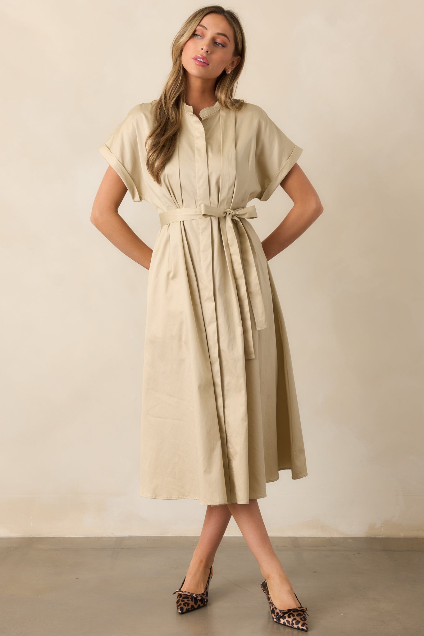This beige dress features wide cap sleeves and a button-up front, blending a relaxed silhouette with tailored details.