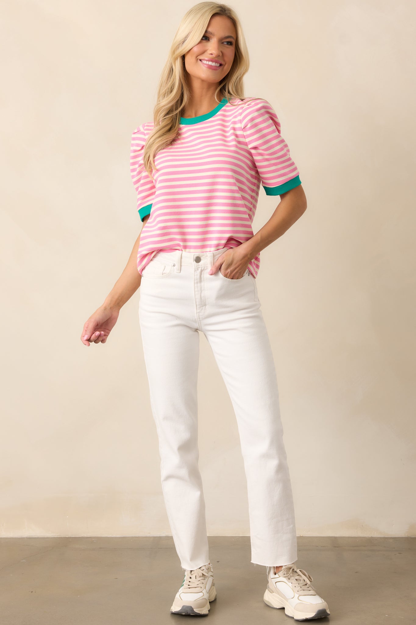 A pink top featuring a round neckline, slightly puffy sleeves, and a contrasting green trim along the collar and cuffs.