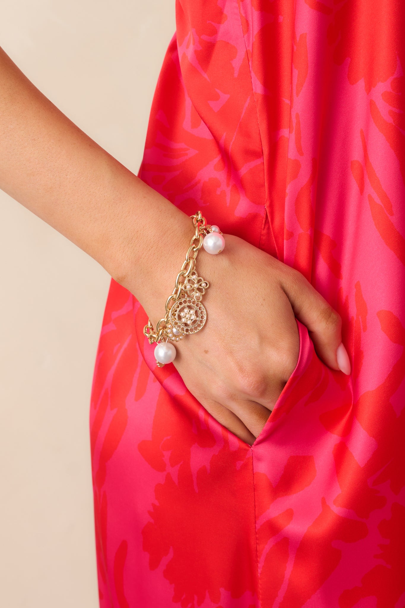 A gold and ivory charm bracelet with a thick gold chain, featuring a mix of circular gold and ivory faux pearl charms.