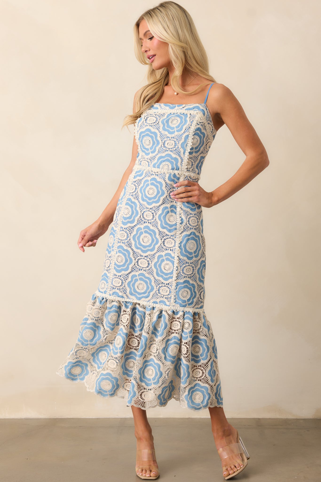 A stylish light blue dress with intricate embroidered eyelet detailing, an eye-catching abstract print, and a scalloped bottom hem, offering a flattering silhouette with adjustable straps.