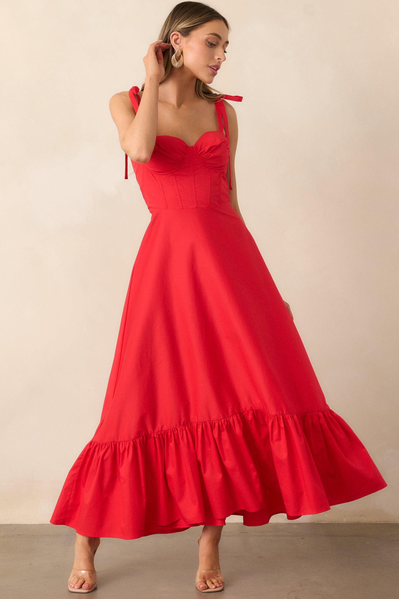 A flattering red dress with a built-in padded bustier, self-tie bow straps, and a flowing tiered skirt that enhances its feminine design.