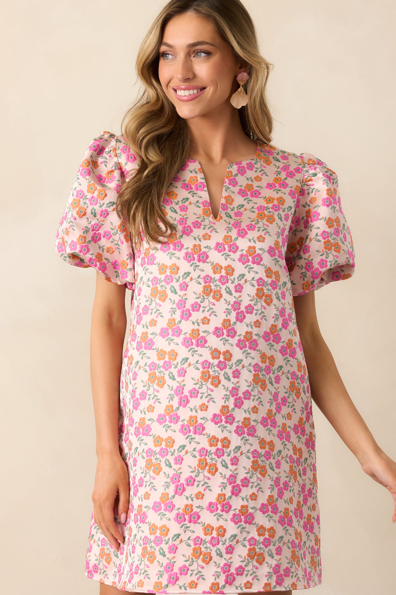 A cropped shot of the mini dress featuring its notch v-neckline and puff sleeve design, highlighting the delicate structure and fabric details.