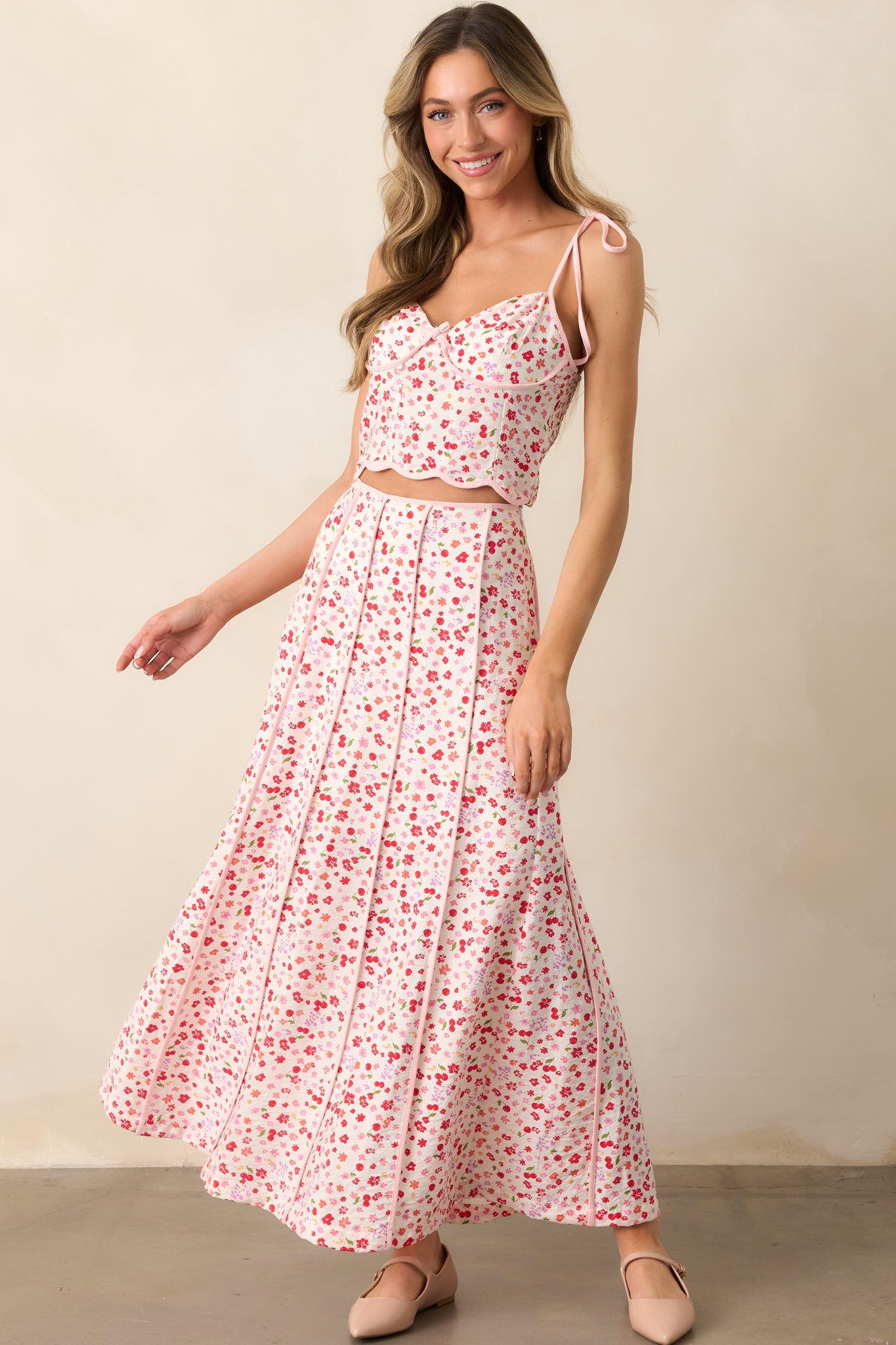 This pink skirt features a vibrant floral and cherry print, a panel design, and delicate pink hem detailing, creating a flattering, feminine silhouette.