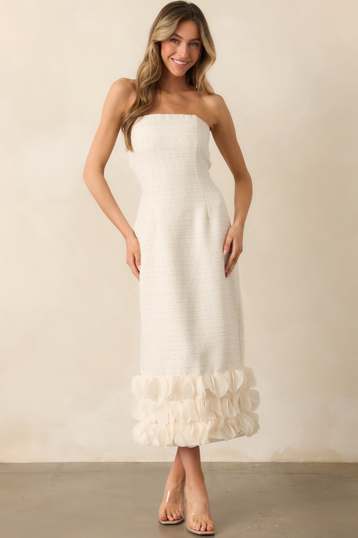 The strapless ivory dress featuring a non-slip strip along the top interior hem for support and a flowing 3D petal bottom tier.