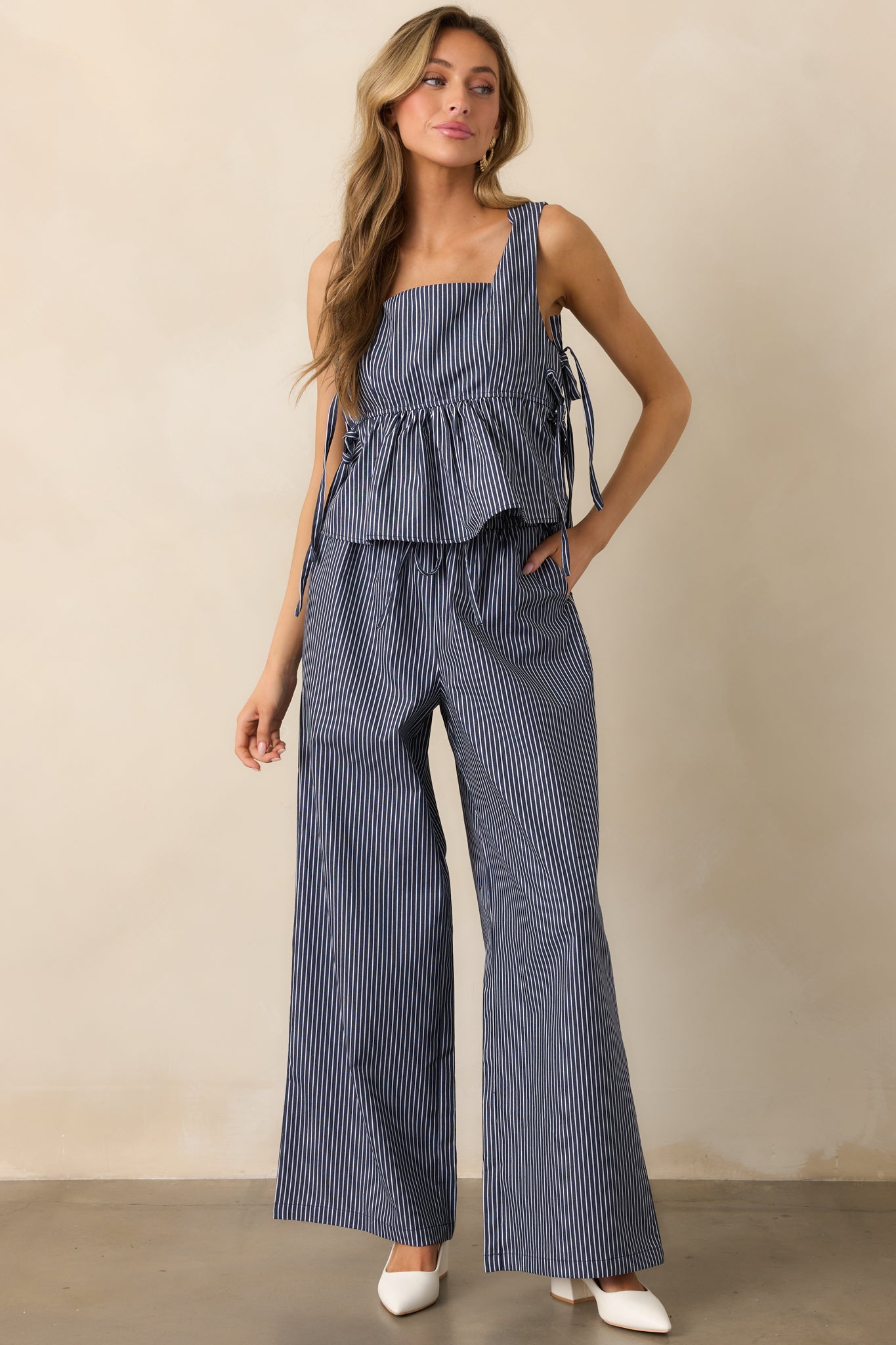 Navy pants with an elastic waistband, adjustable drawstring, and functional pockets, featuring a relaxed fit and stylish striped design.