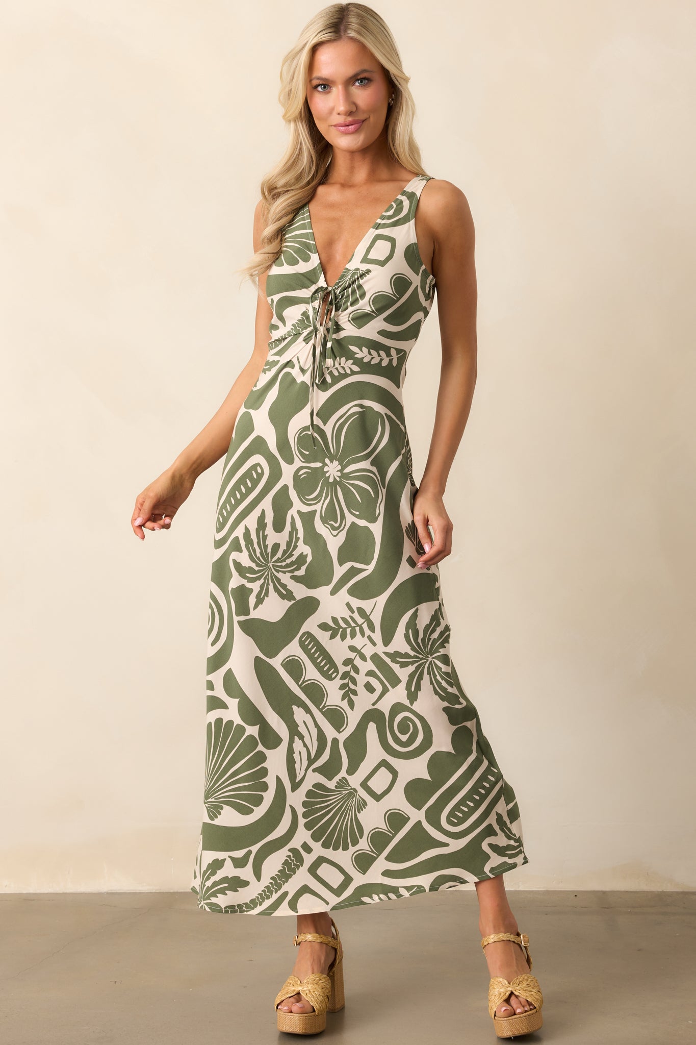 A midi dress with an ivory and green tropical print, featuring a V-neckline and an adjustable self-tie keyhole closure.