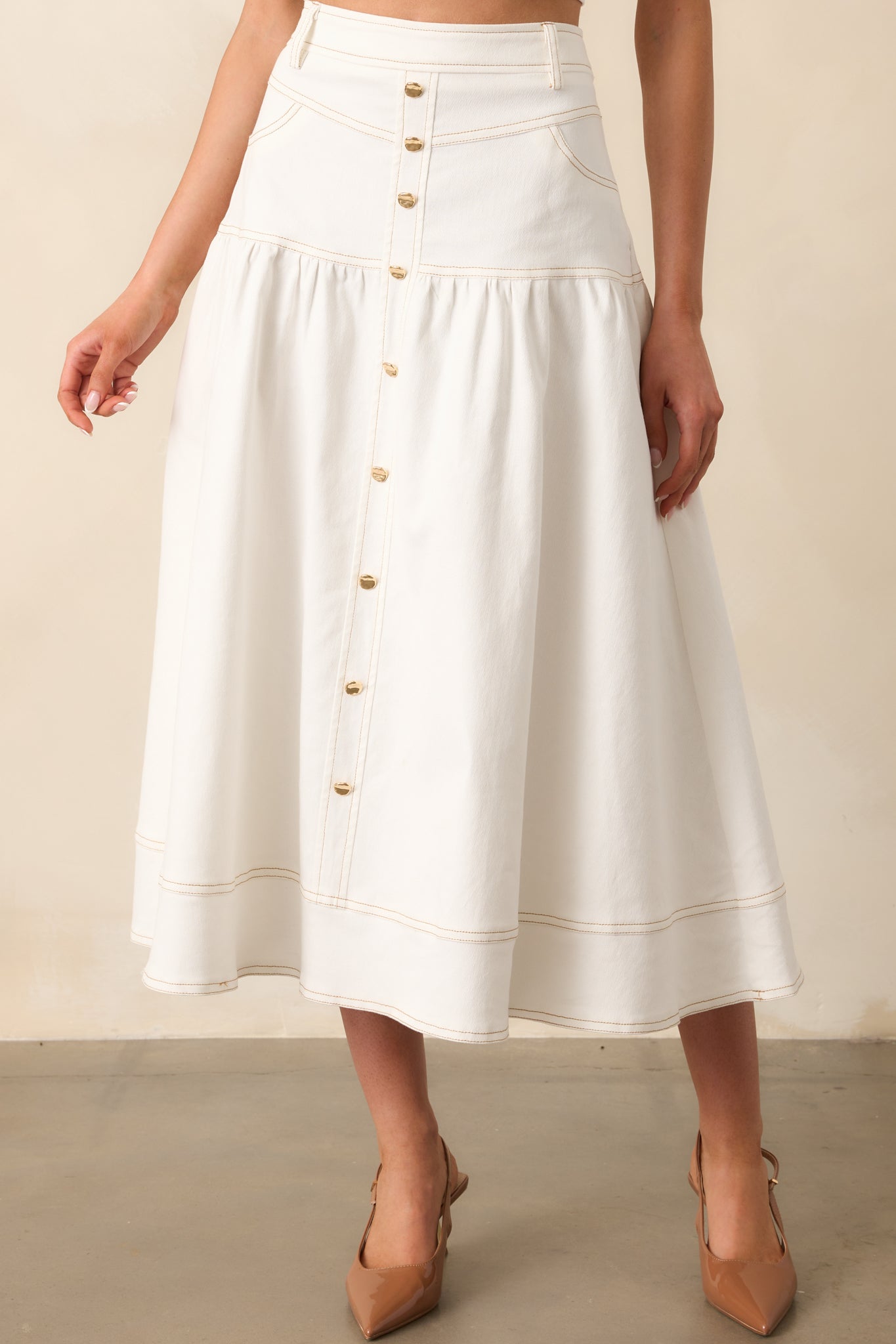 A closer look at the drop waist design and structured details of this white denim maxi skirt.