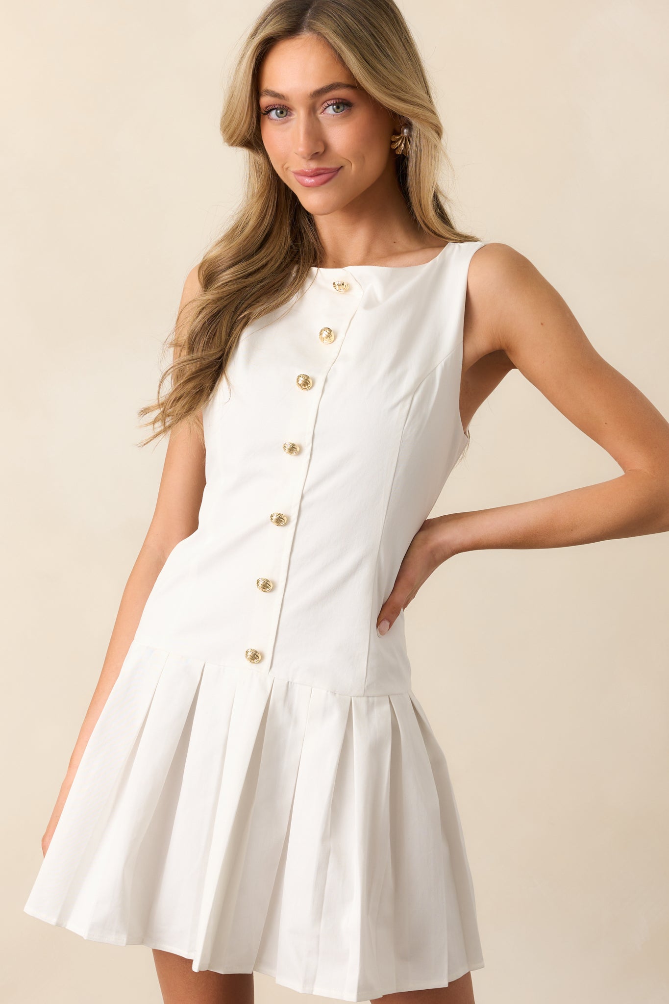 A fresh and elegant white mini dress with a faux button front bodice, round neckline, and pleated skirt. The sleeveless design is perfect for warm weather, while the hidden back zipper closure ensures a smooth silhouette.