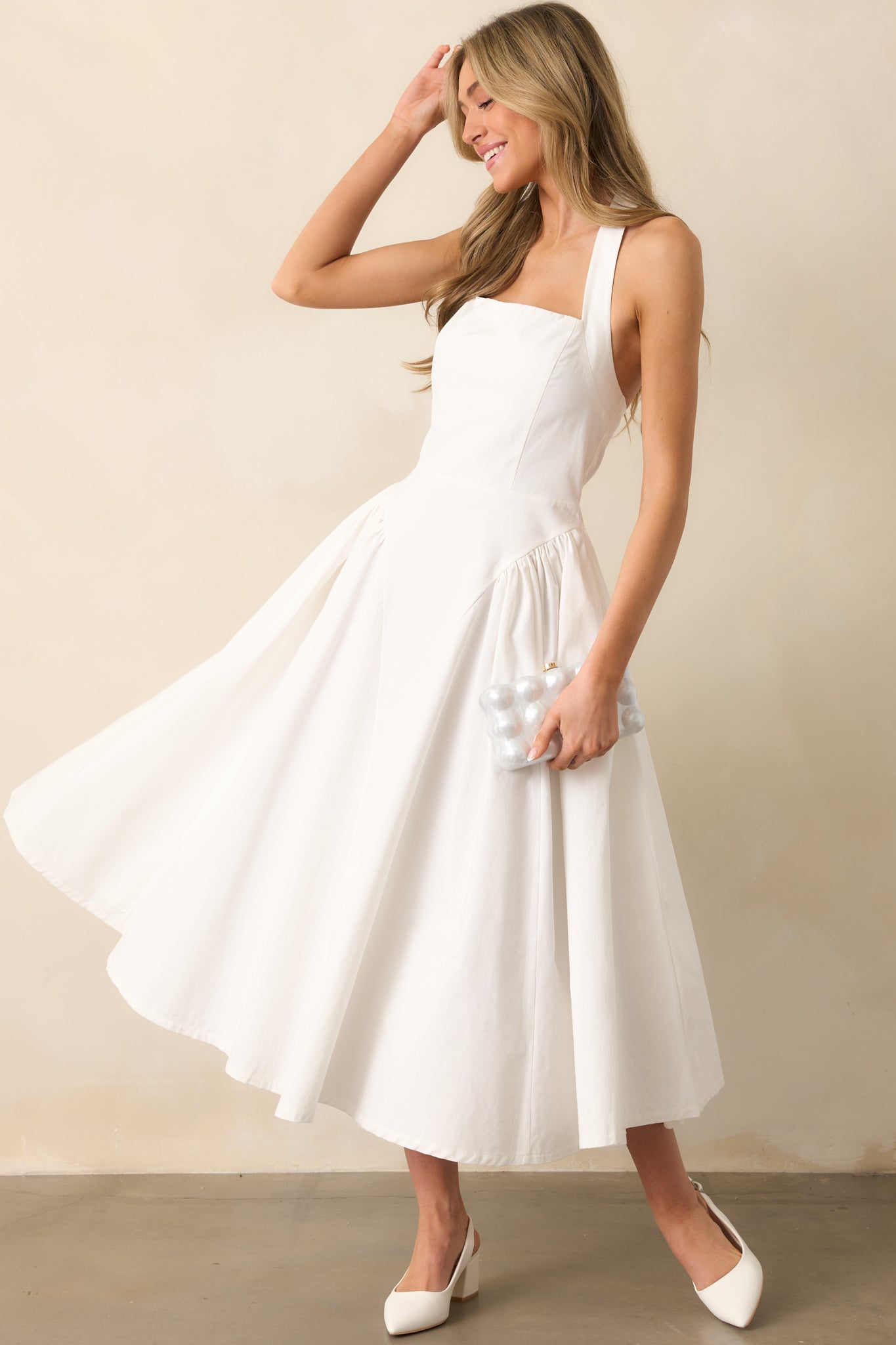A timeless white maxi dress with halter straps secured by two buttons, offering a blend of style and functionality.