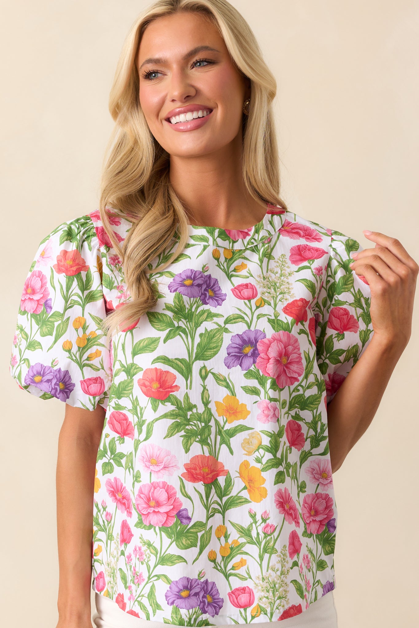 A vibrant top featuring a multicolor floral design, a round neckline, and short puff sleeves with elastic cuffs.